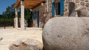 A stone building with a wooden pergola, large rocks, and a stone sculpture. - Altes Steinhaus Goranova Kuca by Interhome (Starigrad-Paklenica)