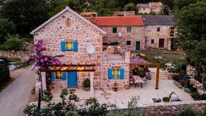 A stone house with a balcony and outdoor seating area, surrounded by greenery and mountains. - Altes Steinhaus Goranova Kuca by Interhome (Starigrad-Paklenica)