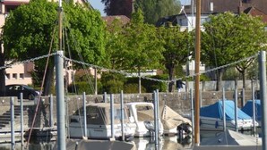 Un port de plaisance avec des bateaux amarrés, une église dont le clocher se détache sur l’horizon, et des immeubles résidentiels à proximité.