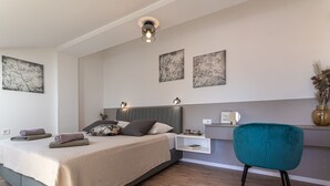 Una camera da letto moderna con un letto, un comodino, una poltrona color acquamarina e opere d'arte alle pareti.