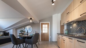Una cucina moderna con zoccolo in piastrelle a spina di pesce, mobili in legno e zona pranzo con tavolo apparecchiato per quattro persone.