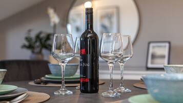 A bottle of wine, two empty wine glasses, and a bowl on a table.
