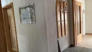 Een hal met een houten deur, een kapstok aan de muur en een ingelijst schilderij.