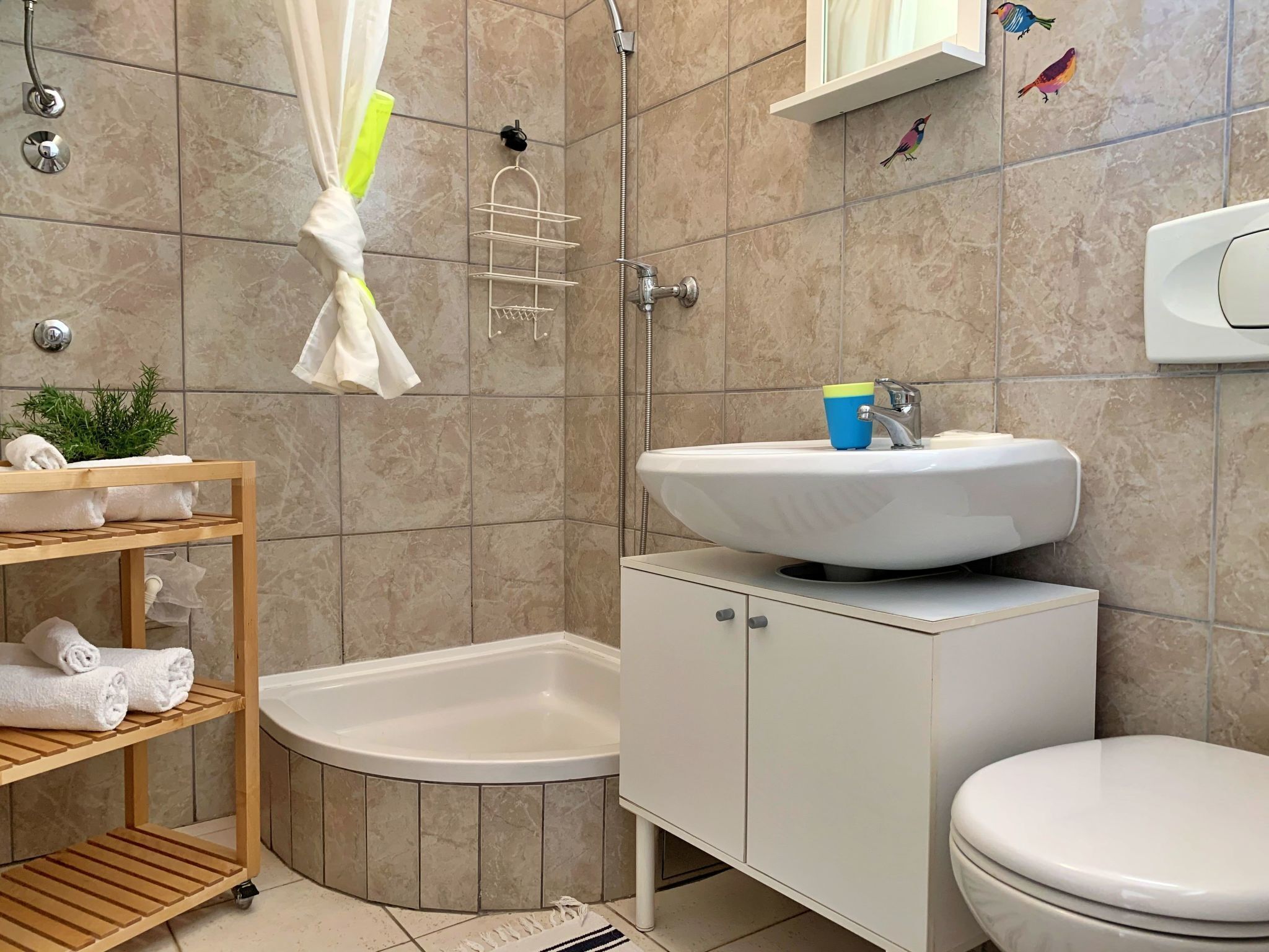 A bathroom with a bathtub, a sink with a cup, a toilet, and a shelf with towels.