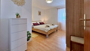 Une chambre à coucher avec un lit, une commode, une petite plante et un luminaire au plafond.
