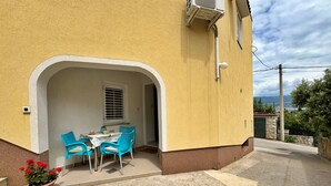 Un bâtiment jaune doté d’un patio abrité, avec une table et des chaises bleues.