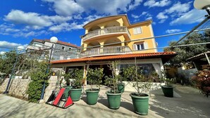 Un edificio a più piani con balconi, piante in vaso e un cielo azzurro limpido.