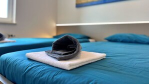 Un letto rifatto con un cappello piegato su un cuscino bianco.