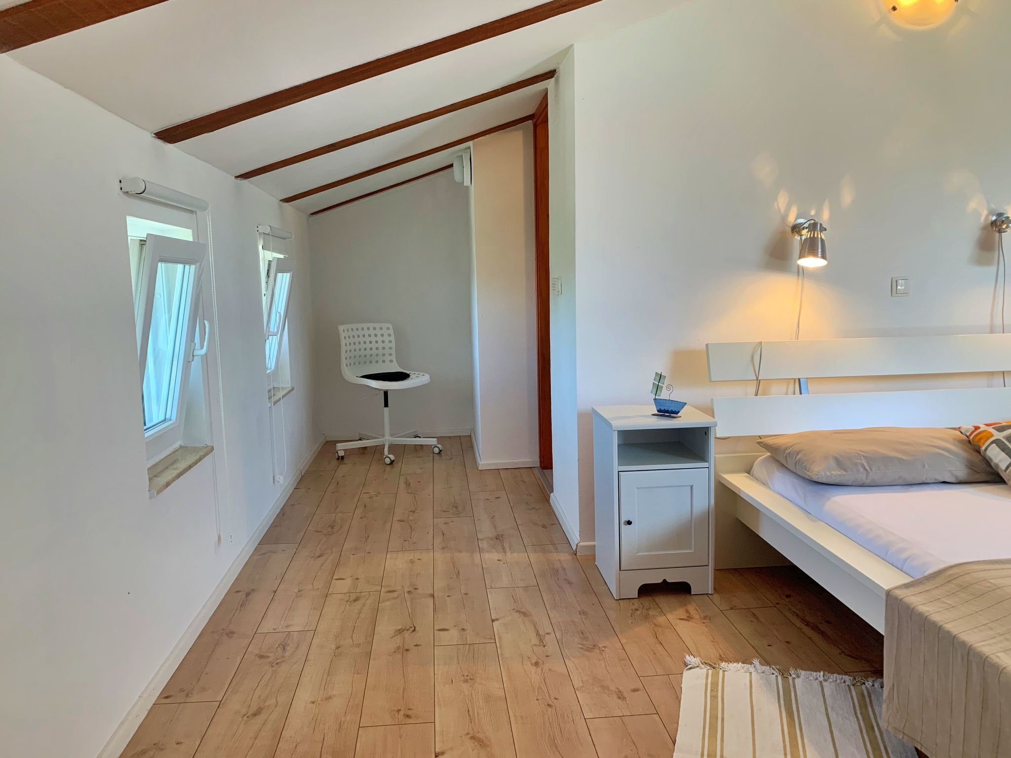 A bedroom with a bed, a nightstand, a chair, and a small table.