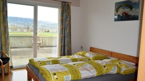 Une chambre à coucher avec un lit, une chaise et une vue sur un balcon et le paysage environnant.