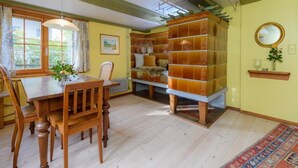 Uma sala de jantar com mesa e cadeiras de madeira, uma estante e um radiador.