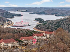 A marina with boats docked, surrounded by forested hills and a residential area with multi-story buildings.