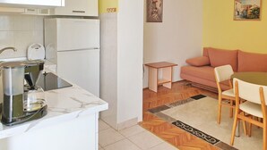 Un angolo cottura funzionale, con macchina del caffè, frigorifero e un piccolo tavolo.