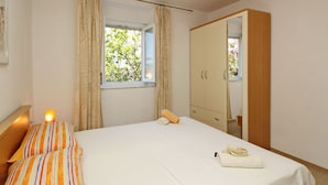 Una camera da letto con un letto, un comodino con una lampada, un armadio e una finestra con tende.