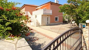 Una casa a due piani con un balcone, un patio piastrellato e un muro in pietra.