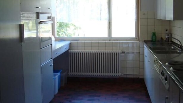 A compact kitchen with a window, a clock, a radiator, and basic appliances. - Hof Eggweid by Interhome (Aesch ZH)