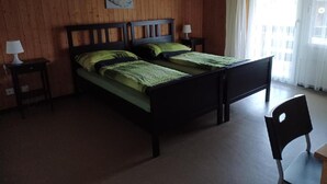 A room with a wooden wall, a bed with green bedding, two bedside tables with lamps, and a chair. - Hof Eggweid by Interhome (Aesch ZH)