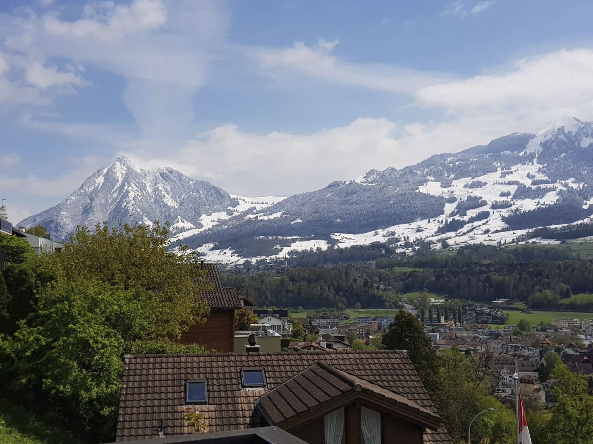 Paisaje montañoso con picos nevados y un pueblo en el valle.