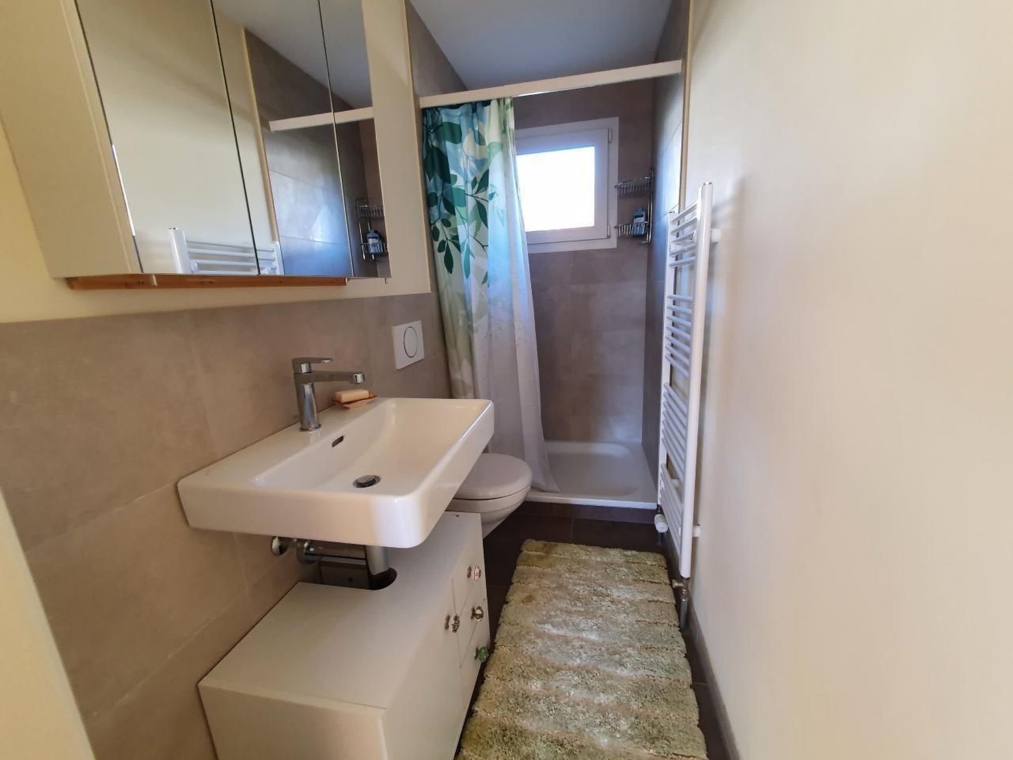 A compact bathroom with a sink, toilet, and shower.