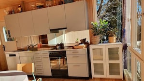 A modern kitchen with wooden cabinets, a built-in oven, and a dining area with a table and chairs.