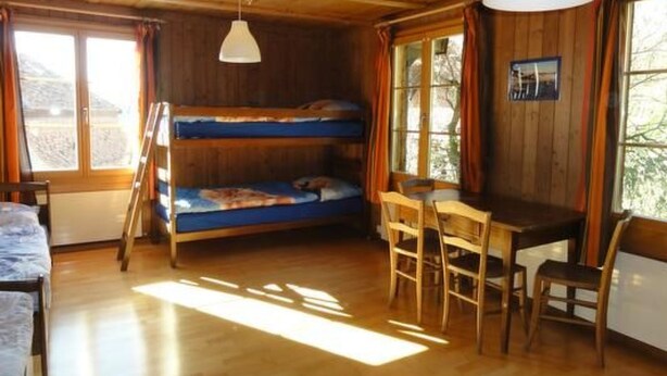 A cozy cabin with a bunk bed, a dining table with chairs, and a hanging light fixture. - Gurtendörfli by Interhome (Wabern)