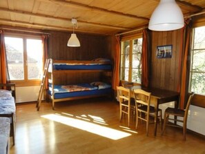 A cozy cabin with a bunk bed, a dining table with chairs, and a hanging light fixture.