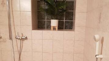 A bathroom with a bathtub, a shower area, and a window with a plant.