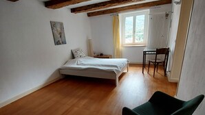 A bedroom with a bed, a chair, a window with curtains, and a radiator. - Giselas Ruheplatz by Interhome (Liesberg Dorf)