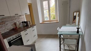 A modern kitchen with white cabinets, a stone backsplash, and a window with a view of the outside. - Giselas Ruheplatz by Interhome (Liesberg Dorf)