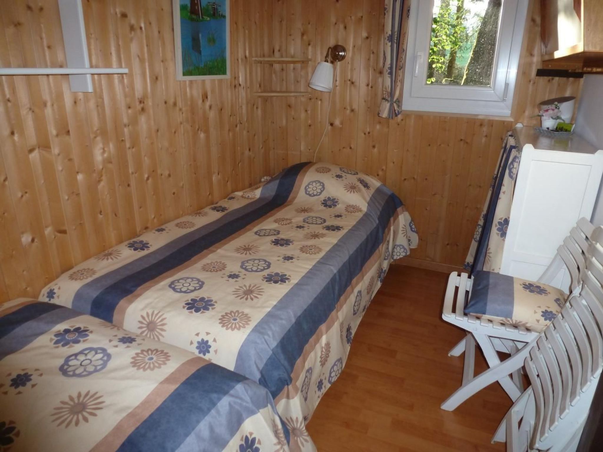 Ein Zimmer mit Holzwänden, zwei Betten, einem Schreibtisch und einem Stuhl.