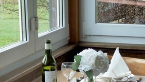 Una mesa de comedor dispuesta con vajilla blanca, una botella de vino y un florero con flores blancas.