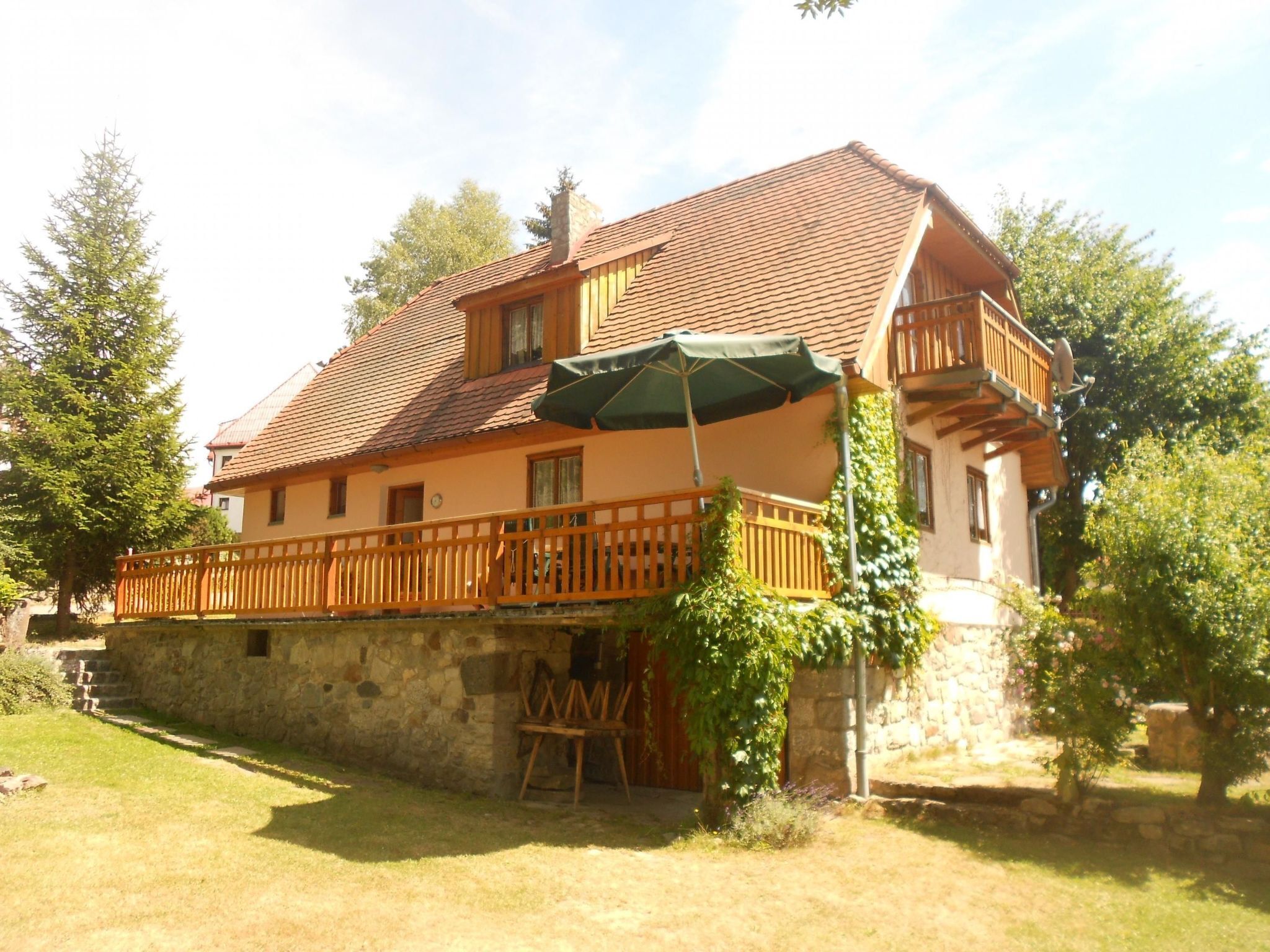 Une maison à deux étages, avec un toit en tuiles, un balcon en bois et un mur en pierre.