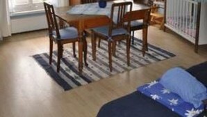 Ein Zimmer mit Esstisch, Stühlen, einem Bett und einem Babybett.