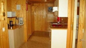 A compact kitchen with wooden walls, a central island, and basic appliances.