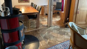 Ein gemütliches Zimmer mit einem Holzespeisetisch, Stühlen, einem roten Herd und einem Spiegel an der Wand.