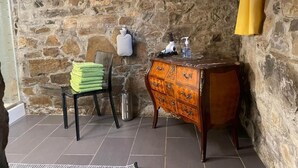 Ein Badezimmer mit Steinwänden, einem Holzausleger und einem Handtuchhalter sowie einem Handtrockner.