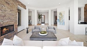A spacious living room with a stone fireplace, a central coffee table, and a modern sofa. - Marvelous 4-bed resort style house with panoramic Mountain Views in La Quinta (La Quinta)