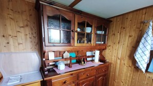 Eine Holzküche mit Küchenschrank, Spüle und einer gefliesten Spritzschutzwand.