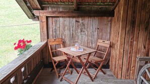 Eine Holzterrasse mit Tisch, Stühlen, einer Bank und einem Blumentopf.
