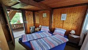 Ein Zimmer einer Holzhütte mit einem Bett, zwei Nachttischen und einem Fenster.