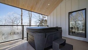 Ein Whirlpool auf einem Balkon mit Blick auf Bäume und eine verschneite Landschaft.