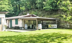 A rustic building with a covered patio, outdoor seating, and a sign indicating a lodging facility. - Insel-Ferienhaus by Interhome (Grono)