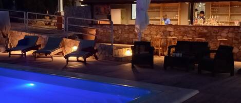 A pool area with lounge chairs and a bar.