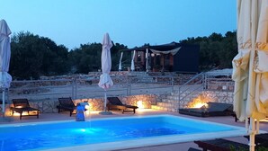 A swimming pool with lounge chairs and umbrellas, surrounded by stone walls and a wooden deck. - Strandhaus Sofia - Ferienanlage Bain, Žut - Kornati by Interhome (Dragišina)