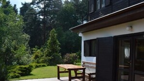 A patio with a wooden table and chairs, surrounded by a garden with various plants and trees. - Haus Cervená nad Vltavou mit Terrasse by Interhome (Jetetice)