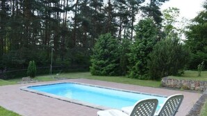 A rectangular swimming pool with a paved deck, surrounded by a grassy area and dense trees. - Haus Cervená nad Vltavou mit Terrasse by Interhome (Jetetice)