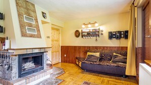 Una sala de estar acogedora con chimenea, piso de madera, un sofá y un comedor.
