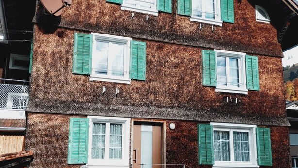 Un immeuble à plusieurs étages, de style architectural traditionnel, caractérisé par un toit à forte pente et des fenêtres en lucarne.