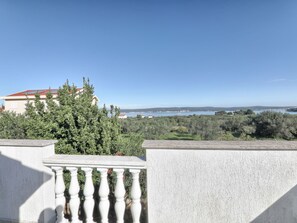 Un balcón con vistas a un paisaje costero, que incluye árboles y una masa de agua distante.