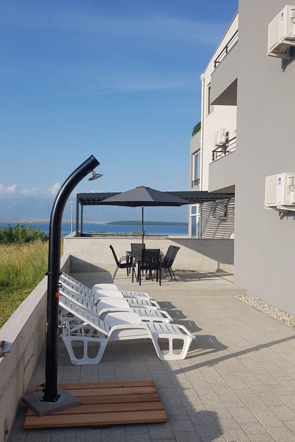 Une terrasse avec des fauteuils, une table et un parasol, donnant sur une étendue d’eau.